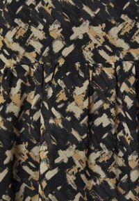 Black fabric with an abstract pattern in beige and gold tones, featuring pleats for texture and visual interest.