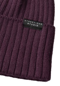 Beanie a maglia di colore viola scuro con costine verticali, caratterizzato da un'etichetta nera con testo bianco che recita "STREET ONE STUDIO." Tessuto morbido e testurizzato.