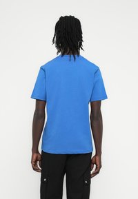 Μπλουζάκι από βαμβάκι σε βασιλικό μπλε χρώμα, με στρογγυλή λαιμόκοψη και κοντά μανίκια, με ομαλή υφή και κανονική εφαρμογή, απεικονιζόμενο από πίσω.