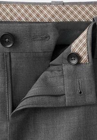 Cinturilla de pantalones grises a medida con botones negros, cremallera y detalle de forro interior a cuadros beige.