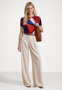 Multicolored geometric print shirt, beige wide-leg trousers, brown belt with "RL" buckle, and tan shoulder bag. Smooth textures and casual style.