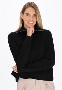 Maglione nero con zip collo, dal fit rilassato, con polsini e orlo a coste, caratterizzato da una texture liscia. Design minimalista con dettaglio della zip in argento.
