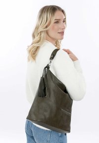 Olive green leather shoulder bag with a slouchy design, tassel accent, and a zippered pocket on the side. Smooth texture, large shape.