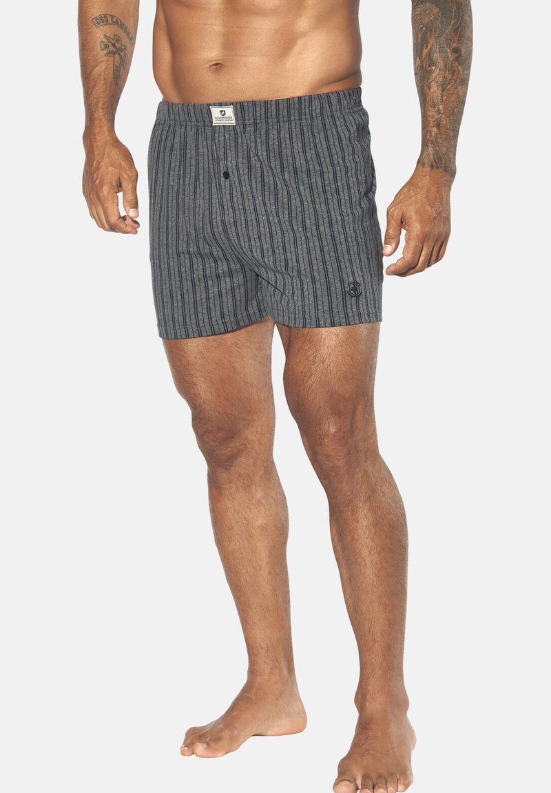 Boxershorts in Dunkelgrau mit vertikalen weißen Streifen, elastischem Bund, Knopfverschluss und kleinem Logo auf der unteren linken Seite.