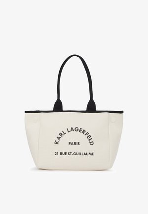 Kermanvärinen kangaskassi, jossa mustat kahvat ja reunat. Kassi on varustettu painetulla tekstillä: "KARL LAGERFELD PARIS 21 RUE ST-GUILLAUME." Rakenteellinen muotoilu.