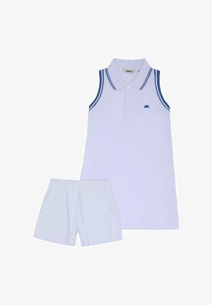 Mouwloos witte polojurk met blauwe bies aan de kraag en armgaten, gecombineerd met witte shorts met elastische taille.