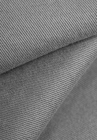 Tela de denim gris con un fino y consistente patrón de espiga. Textura suave, ligeramente arrugada, que destaca su estructura tejida y profundidad de color.