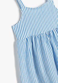 Robe sans manches à rayures bleues et blanches avec une taille froncée et un tissu léger au toucher doux. Le motif rayé est parfaitement espacé.