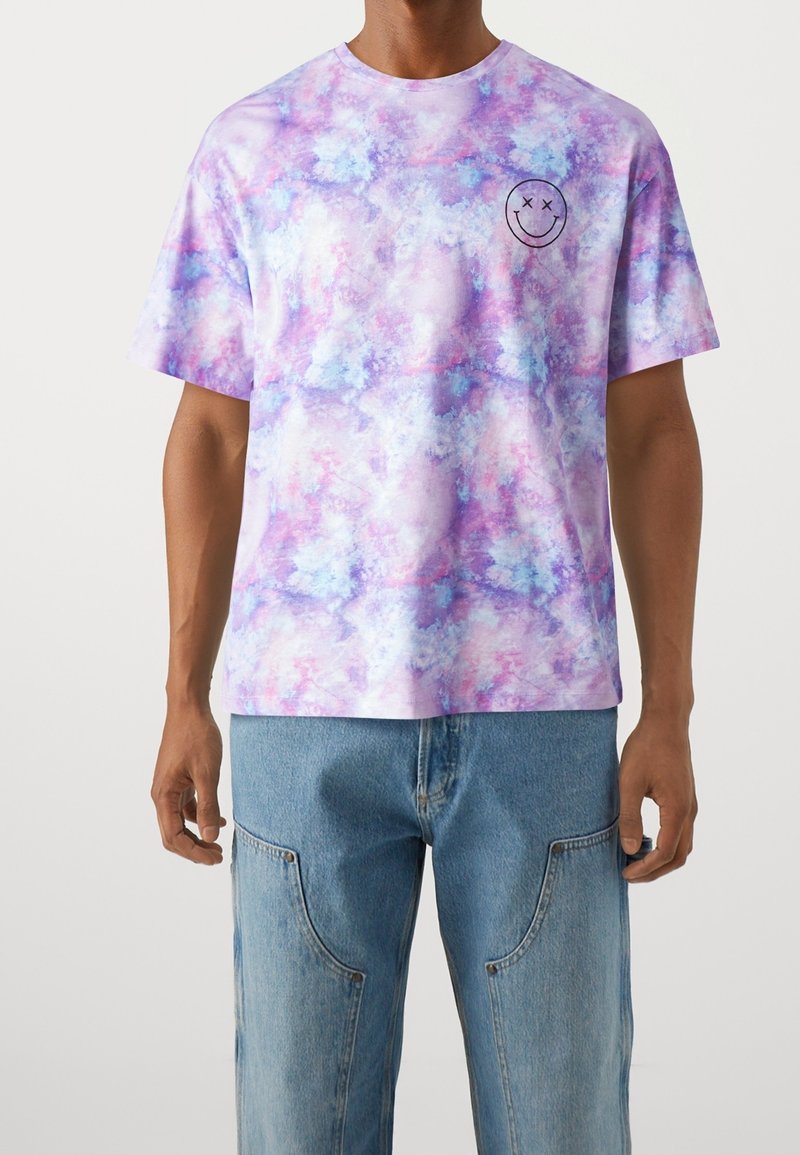 Purple and light blue tie-dye graphic T-shirt with a smiley face design on the left chest. Relaxed fit and cotton material.