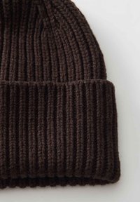 Brown knitted beanie with vertical ribbing. Features a folded cuff for added warmth and texture. Made from soft, warm yarn.