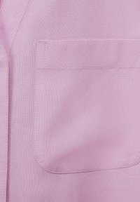 Tessuto rosa chiaro con una texture liscia, dotato di una tasca quadrata e cuciture precise. Design minimalista, senza hardware o decorazioni visibili.