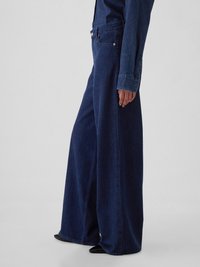Pantaloni din denim cu picioare largi, de culoare albastru închis, având talie înaltă, design cu cinci buzunare și cusături pe latură. Materialul are o textură netedă și rezistentă.