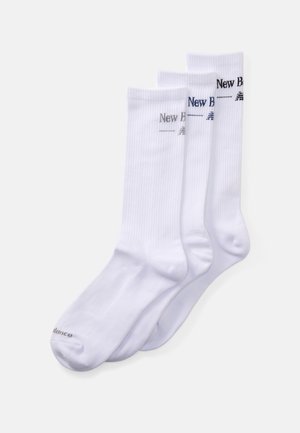 Trois paires de chaussettes blanches mi-mollet avec des bords côtelés et le logo "New Balance" en noir, gris et bleu marine sur le dessus.