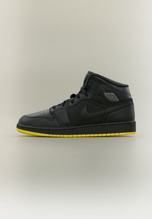 Čierne vysoké tenisky Nike Air Jordan s perforovanými bočnými stranami a žltou podrážkou na jednoduchom neutrálnom pozadí.