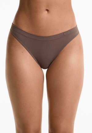 Perizoma marrone, senza cuciture, realizzato in un tessuto morbido e elasticizzato, con una vita sottile e un'etichetta dettagliata sul davanti. Texture liscia e design aderente.