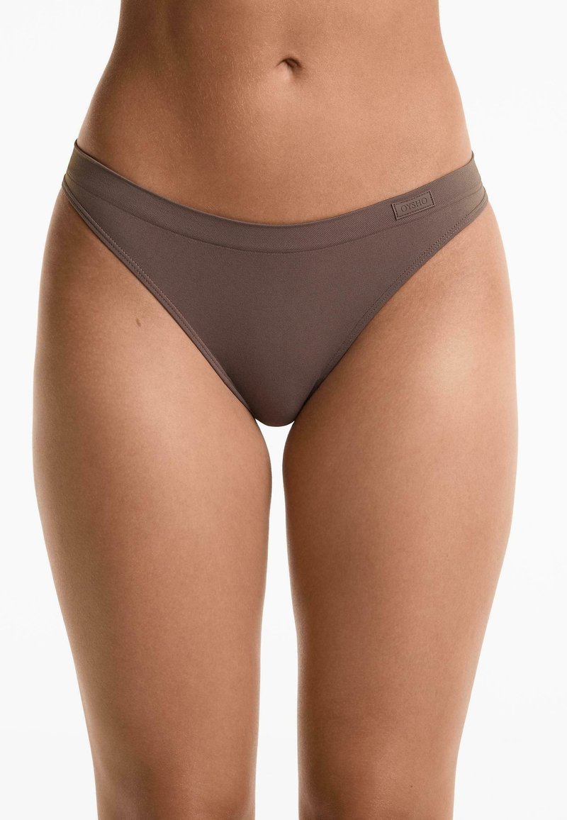 Bruine, naadloze slip met een zachte, rekbare stof, een smalle tailleband en een label detail aan de voorkant. Gladde textuur en getailleerd ontwerp.