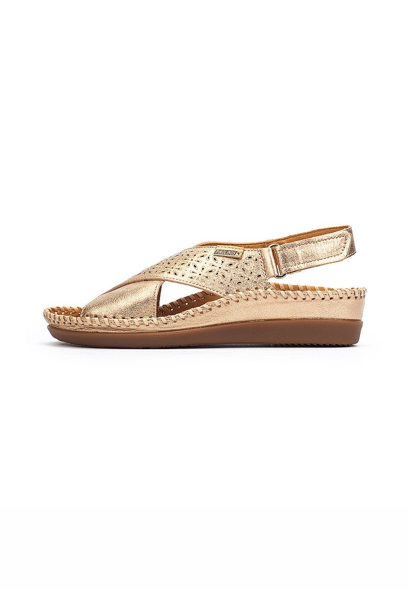 Sandales à bride dorées en métal avec un design floral découpé, en cuir texturé, une sangle arrière, et une semelle compensée basse avec un détail tressé.