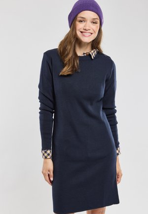 Navy gebreide jurk met lange mouwen en een kraag van een geruite shirtonderlaag bij de manchetten. Eenvoudig, recht gesneden ontwerp.