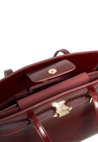 Burgundy leather handbag with gold hardware, featuring a top flap, interior pockets, and smooth texture, displaying a clean, structured design.