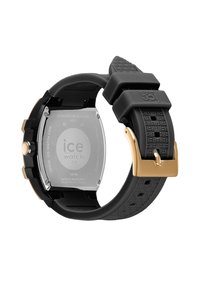 Juodas gumos laikrodžio dirželis su tekstūruotu raštu, aukso spalvos detalėmis ir kvadratiniu nerūdijančio plieno korpusu, pažymėtu "ICE Watch".