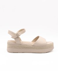 Beige platform sandals with a smooth upper, open toe, and adjustable ankle strap. Textured sole with braided accents around the base.