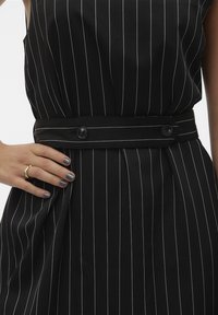 Robe noire à rayures discrètes avec une taille cintrée, un tissu au toucher doux et une ceinture assortie, fermée par deux boutons noirs.