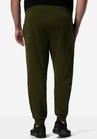 Olijfgroene joggingbroeken met een taps toelopende fit, elastische tailleband en zijzakken. Gemaakt van zacht materiaal met een gladde textuur.