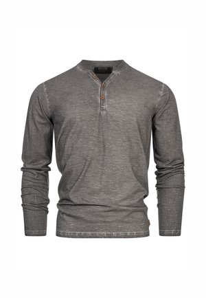 Maglietta henley grigia a maniche lunghe realizzata in tessuto morbido, dotata di una chiusura con bottoni in legno e un design dalla vestibilità rilassata.