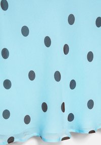 Tissu bleu clair avec un motif à pois noirs régulièrement espacés et un bord doux légèrement froncé.