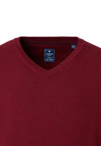 Burgunderfarbener V-Ausschnitt-Pullover aus weichem Strickstoff, mit einem Etikett mit der Marke "Redmond" und der Größe "M" im Kragen.