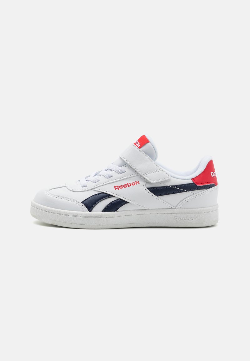 Zapato deportivo blanco con detalles en marino, cierre de cordones y tira de Velcro, cuello acolchado, suela de goma y logo de Reebok en la lengua y el talón.