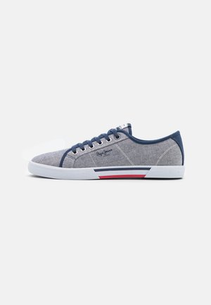 Lavtops afslappet sneaker med grå tekstiloverdel, marineblå kant, hvid gummisål med røde og marineblå striber og marineblå snørebånd.