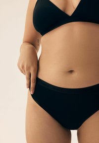 Czarny biustonosz bikini w trójkątnym wzorze i regulowanymi ramiączkami. Pasujące czarne majtki bikini z miękkim, elastycznym pasem. 