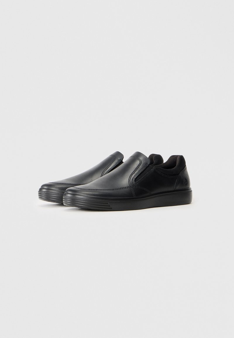 Svarta slip-on skor med en slät läderöverkäst, elastiska sidopaneler och en texturerad gummisula. Har en subtil logotyp nära hälen.