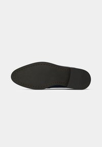 Sole of a dark brown leather dress shoe with visible stitching and a small heel, shown against a plain white background.