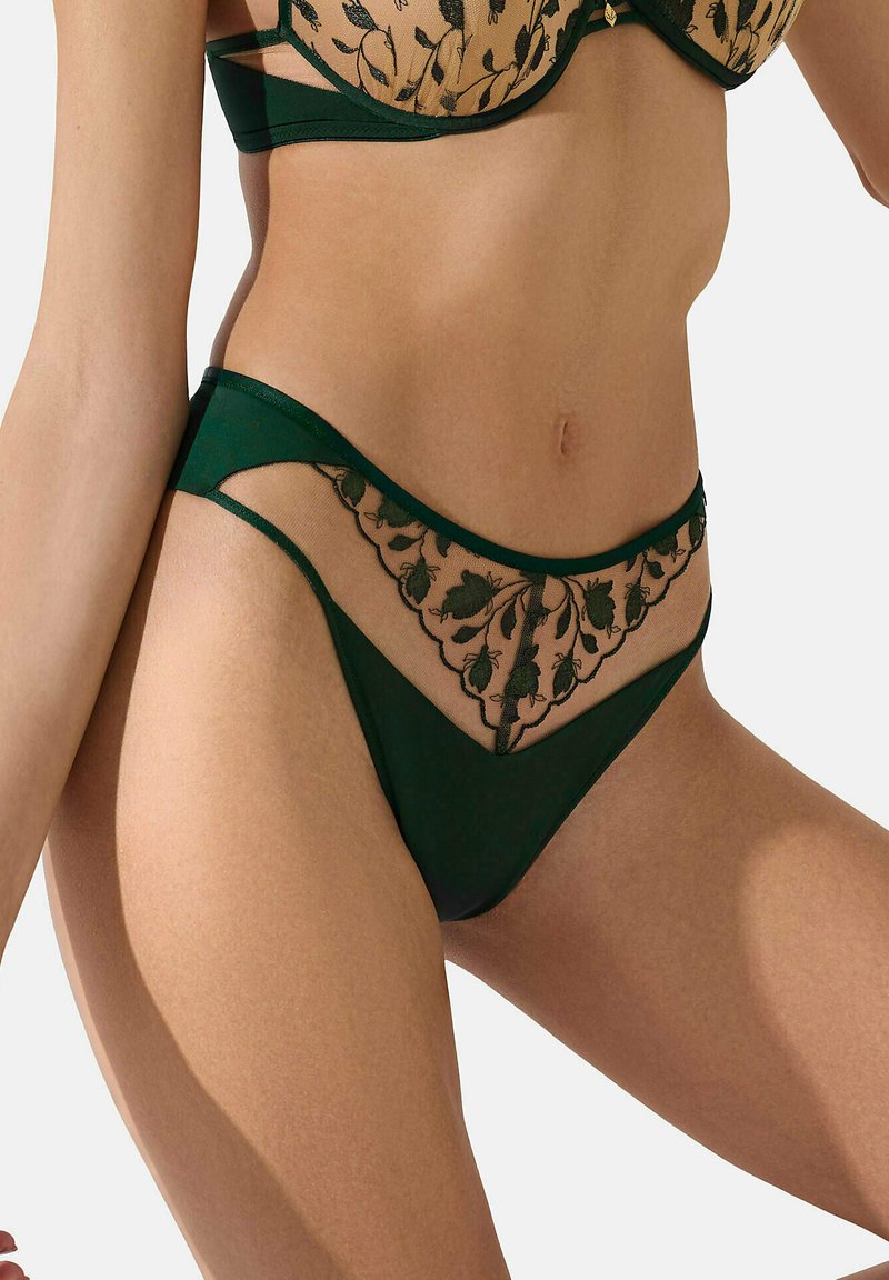 String vert avec des bordures en dentelle, comportant un panneau en mesh transparent orné de broderies florales. Matériau doux avec une coupe élégante et basse.