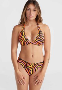 Bikini súprava s trojuholníkovým vrchom a nízkymi nohavičkami, vyrobená z elastického materiálu s odvážnym vzorom oranžovej, ružovej a čiernej farby v zakrivených líniách.