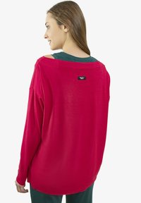 Bluzka z długim rękawem, luźnym krojem w jasnoczerwonym materiale, z szerokim dekoltem i haftowaną metką z logo na plecach.