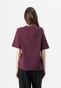 Burgunderrød t-skjorte med korte ermer og klassisk rund hals, laget av myk bomull; har en løs passform og minimalistisk design.
