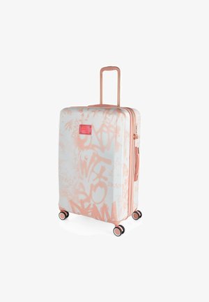 Maleta rígida con una superficie blanca brillante y patrones de graffiti en rosa. Cuenta con un asa retráctil y cuatro ruedas negras para mayor movilidad.