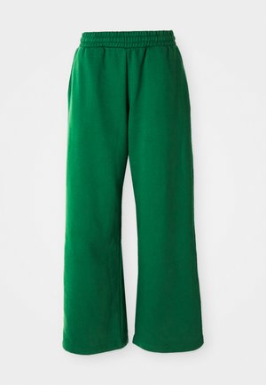 Zielone, luźne dresy wykonane z miękkiego materiału. Posiadają elastyczny pasek w talii, boczne kieszenie oraz szerokie nogawki o gładkiej strukturze.