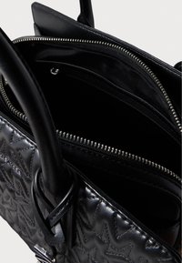 Μαύρη δερμάτινη τσάντα χειρός με κεντημένο αστέρι, διπλές λαβές και φερμουάρ σε θήκη. Το εσωτερικό είναι από μαύρο ύφασμα με θήκες και φερμουάρ.