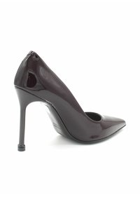 Pump con tacco alto realizzato in vernice bordeaux lucida, con punta appuntita e design con ritagli ai lati. Tacco a stiletto sottile.