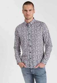 Chemise boutonnée présentant un motif floral en noir, blanc et rose sur un fond clair, avec un col et des manches longues.