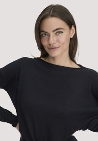 Schwarzes Longsleeve-Oberteil mit lockerem Schnitt und weitem Ausschnitt, aus weichem Stoff gefertigt. Bietet einen eleganten Fall und minimalistische Details.