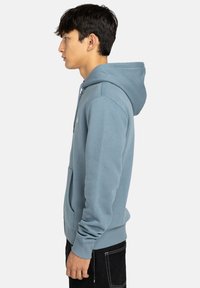 Felpa con cappuccio di colore azzurro chiaro, realizzata in tessuto morbido. Presenta una tasca frontale, polsini a costine e cappuccio con cordino regolabile.