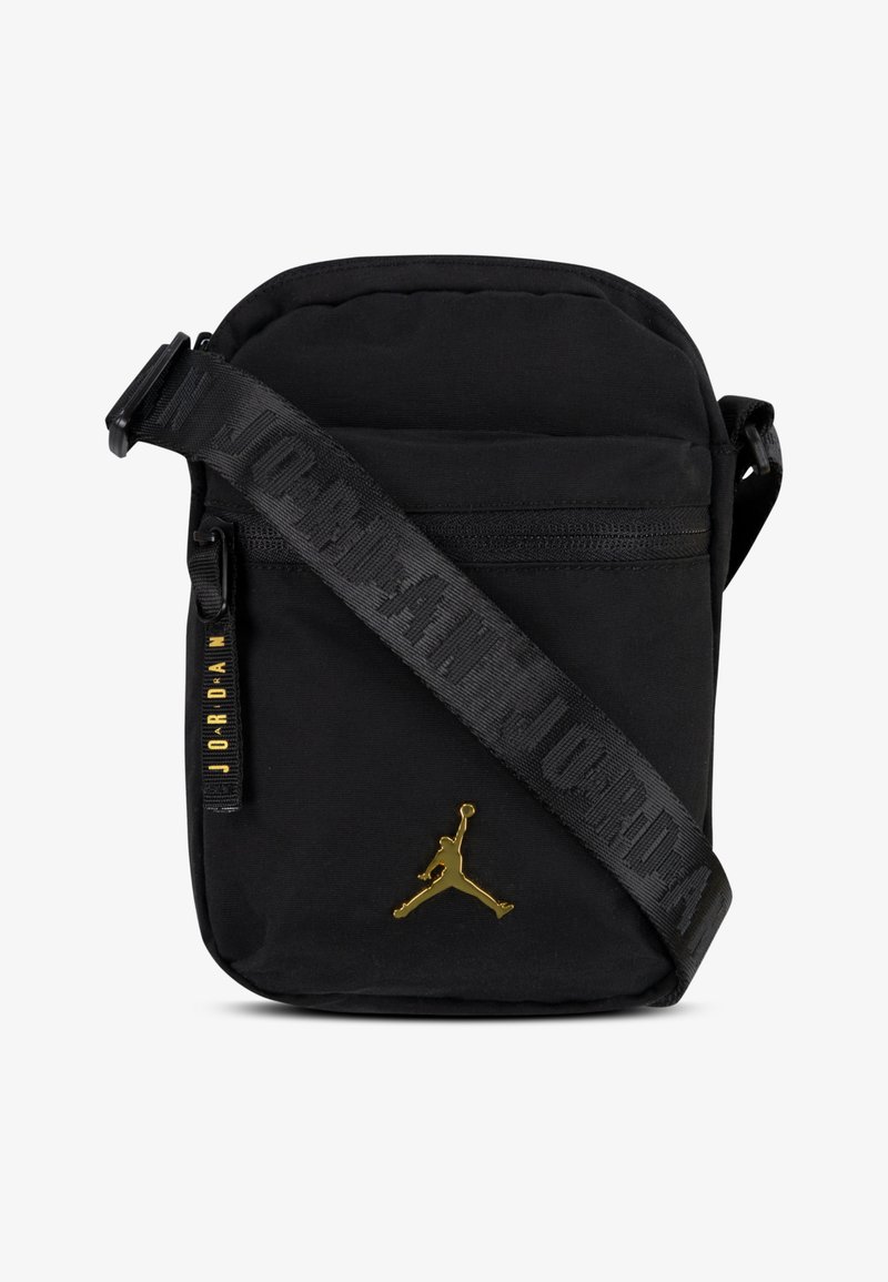 Črn tkaninski torba čez ramo z zlatim Jumpman logotipom, z zadrgo in teksturirano naramnico, na kateri je v izbočenih črkah napisano "JORDAN".