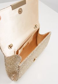 Gold glitter clutch handbag with a satin lining. Features a snap closure, interior card slot, and rounded edges. Sparkling texture throughout.