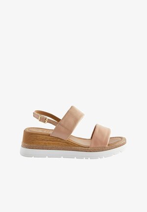 Blush leather sandal with two wide straps, adjustable ankle buckle, and a wooden-style wedge heel. Features a white rubber sole and subtle shimmer.