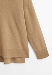 Ljusbrun tröja med en mjuk textur, med ribbade manschetter och nederkant, samt en avslappnad och lös passform.